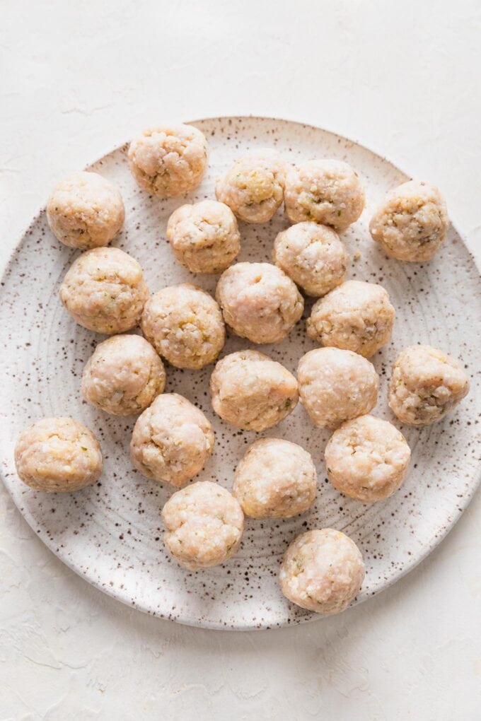 Uncooked chicken Parmesan meatballs, shaped into balls and ready to brown.