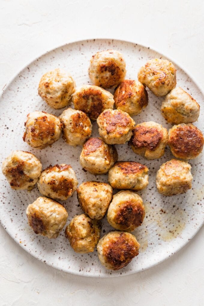 Browned chicken Parmesan meatballs resting on a clean plate.