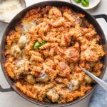Large cast iron skillet with a chicken Parmesan pasta bake made of meatballs, pasta, and a simple homemade tomato sauce.