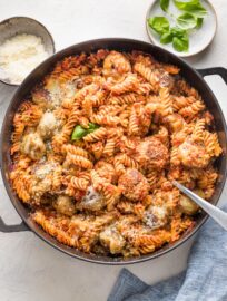 Large cast iron skillet with a chicken Parmesan pasta bake made of meatballs, pasta, and a simple homemade tomato sauce.