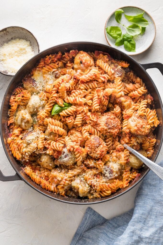 Large cast iron skillet with a chicken Parmesan pasta bake made of meatballs, pasta, and a simple homemade tomato sauce.