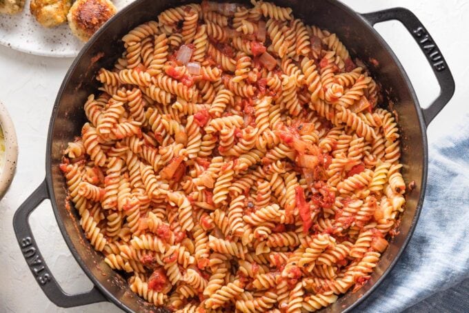 Pasta and sauce mixed together in skillet.