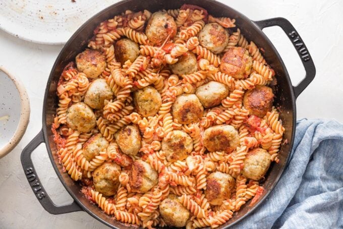 Meatballs nestled into pasta, sauce, and cheese mixture.