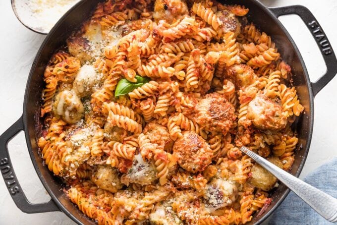 Finished chicken Parmesan pasta bake, fully cooked and being served with a large spoon.