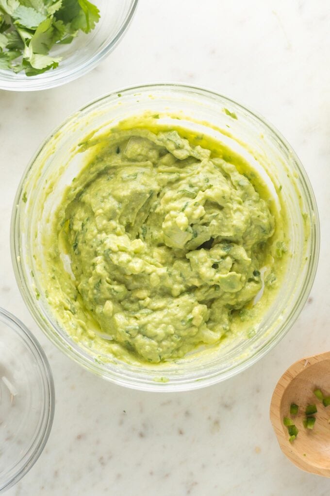 Freshly-mixed homemade guacamole in a mixing bowl, ready to serve.