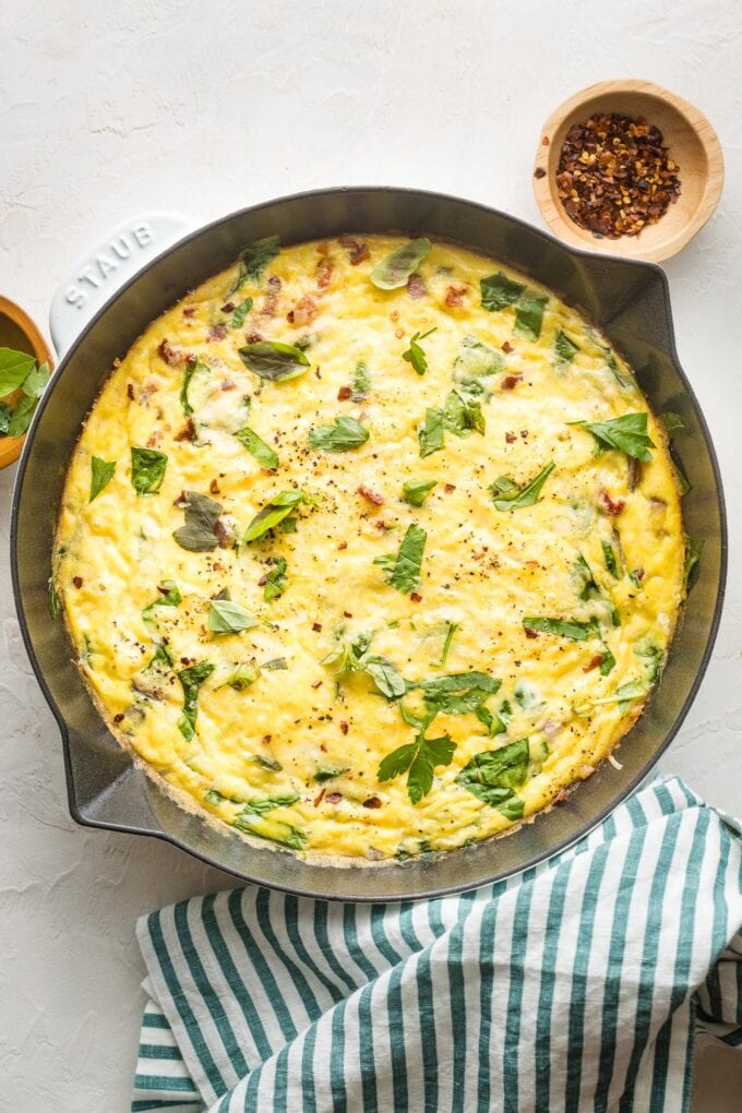 Spinach Parmesan frittata in a white cast-iron skillet, ready to serve.