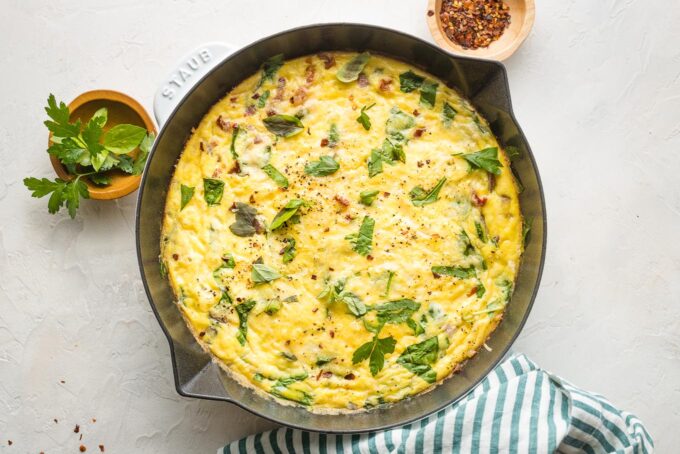 Spinach Parmesan frittata in a white cast-iron skillet, ready to serve.