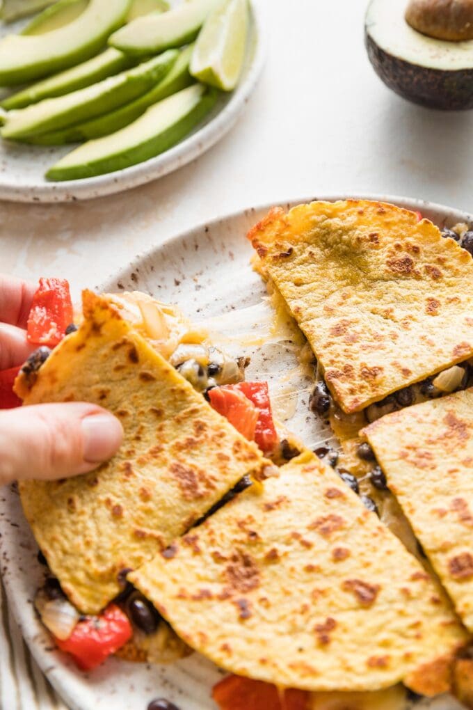 Close up of a cheese pull as two wedges of quesadilla are pulled apart.