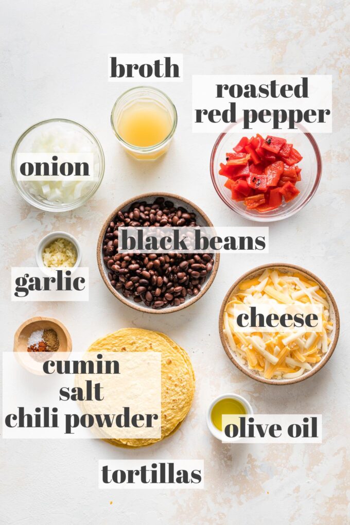 Labeled photo of black beans, tortillas, shredded cheese, onion, roasted red pepper, broth, garlic, cumin, chili powder, salt, and olive oil arranged in prep bowls.