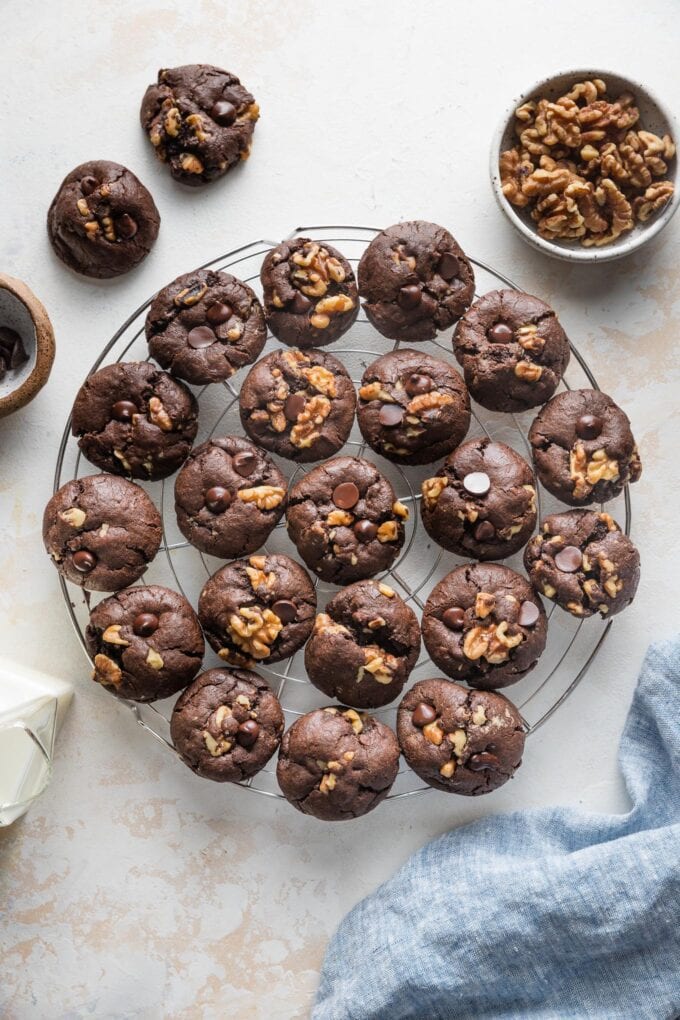 White countertop with a cooling rack filled with double chocolate espresso cookies with walnuts.