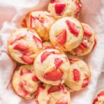 Close up of strawberry banana muffins heaped in a basket lined with a pink kitchen towel.