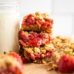 Close-up of three stacked strawberry rhubarb crumble bars.