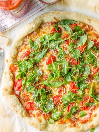 Pizza with marinara sauce, bacon, pan-roasted tomatoes, and fresh arugula. Fresh and delicious!