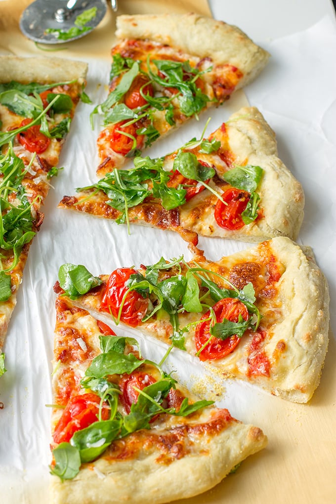 Pizza with marinara sauce, bacon, pan-roasted tomatoes, and fresh arugula. Fresh and delicious!