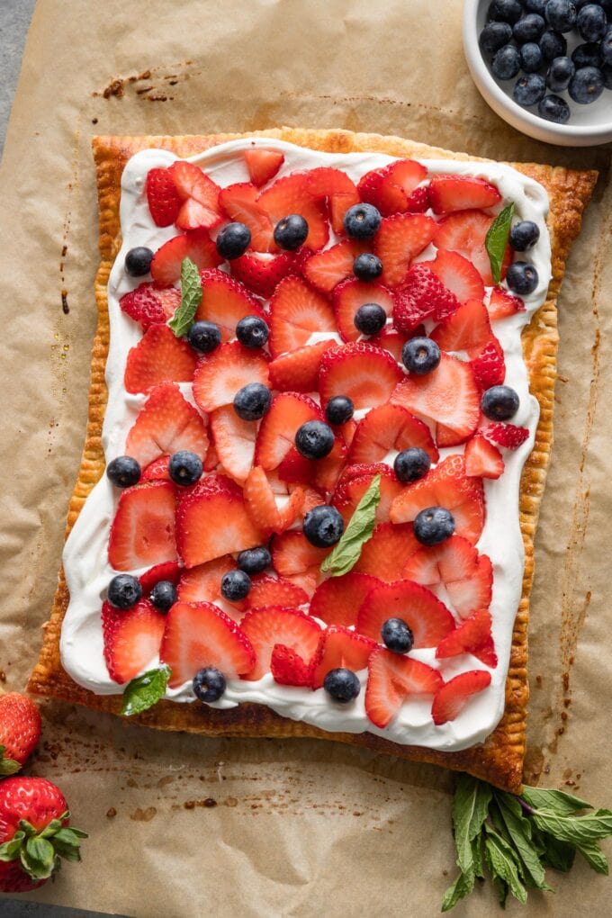 Whipped mascarpone puff pastry tart with fresh berries and mint leaves.