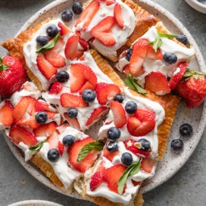 Plate full of slices of whipped mascarpone puff pastry tart with fresh berries.
