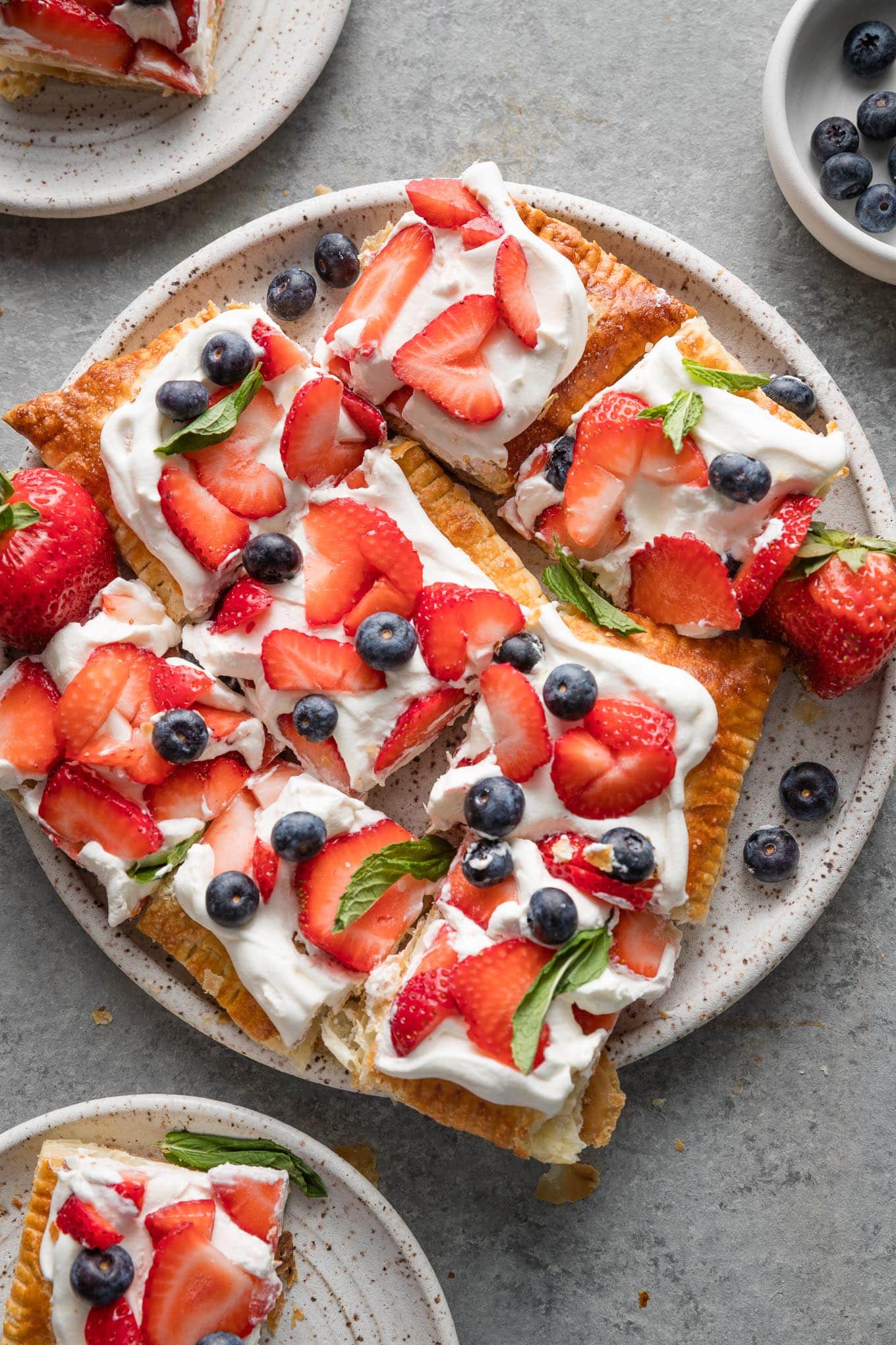Plate full of slices of whipped mascarpone puff pastry tart with fresh berries.