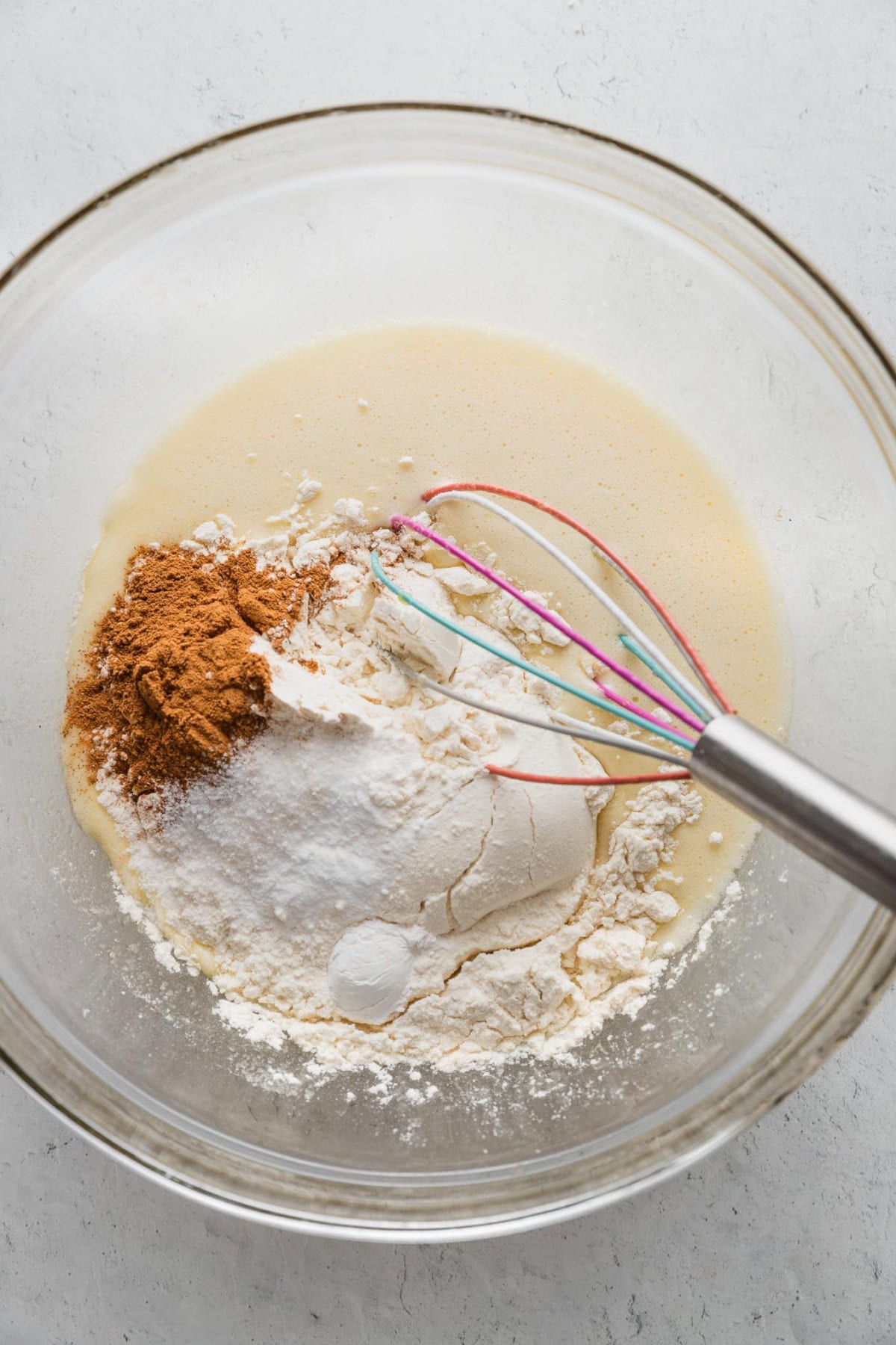 Dry muffin ingredients sprinkled directly on top of wet muffin ingredients, to show an effective one bowl technique.