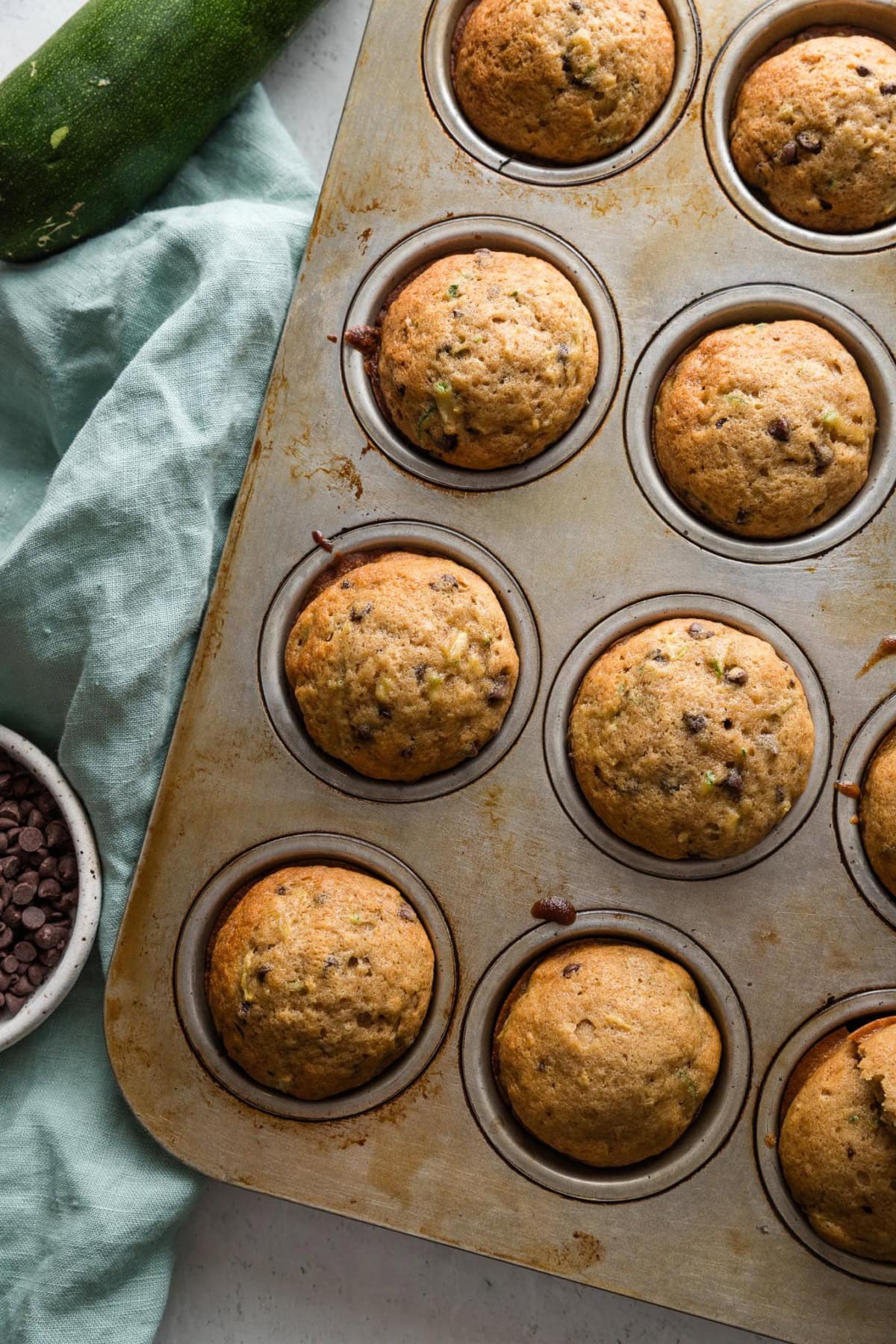 Metal muffin tray filled with chocolate chip zucchini muffins, just removed from the oven.