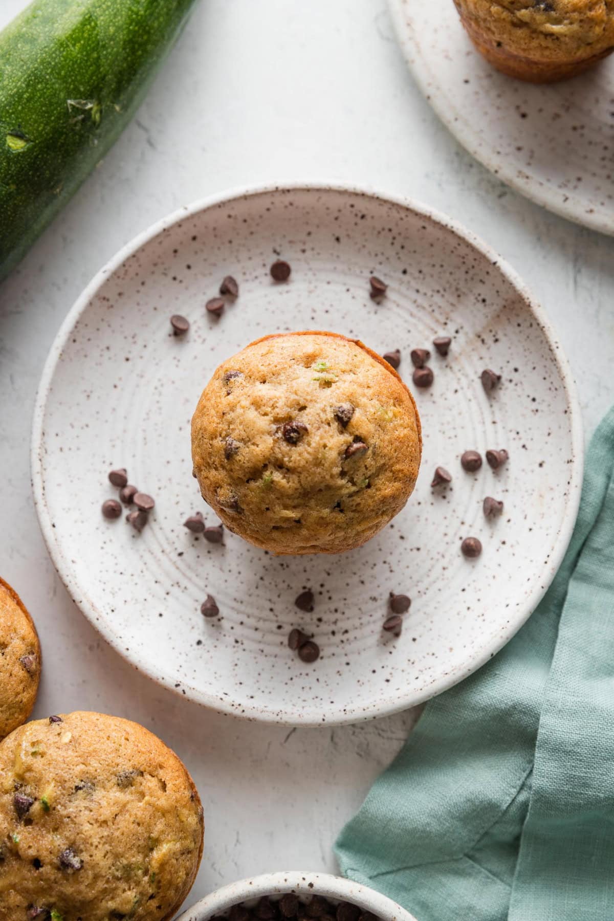 One zucchini chocolate chip muffin resting on a small plate, ready to serve.