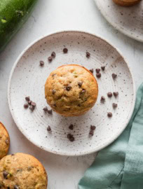 One zucchini chocolate chip muffin resting on a small plate, ready to serve.
