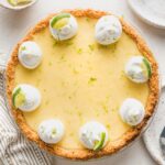 Overhead image of a whole key lime pie garnished with whipped cream, lime slices, and lime zest.