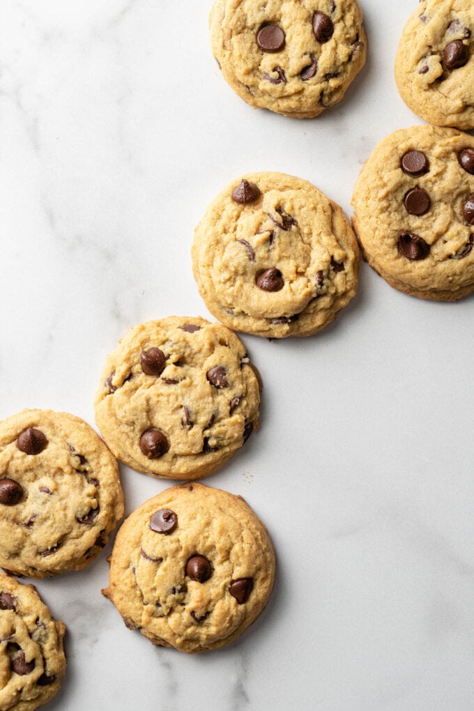 Chocolate chip cookies spread out on a marble countertop.