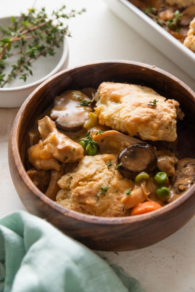 Wooden bowl full of a helping of biscuit topped chicken pot pie.