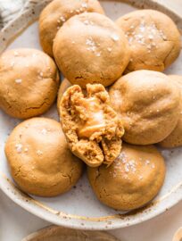 Close up image of a caramel-stuffed molasses cookie broken in half to show the chewy, stretchy caramel melted in the middle.