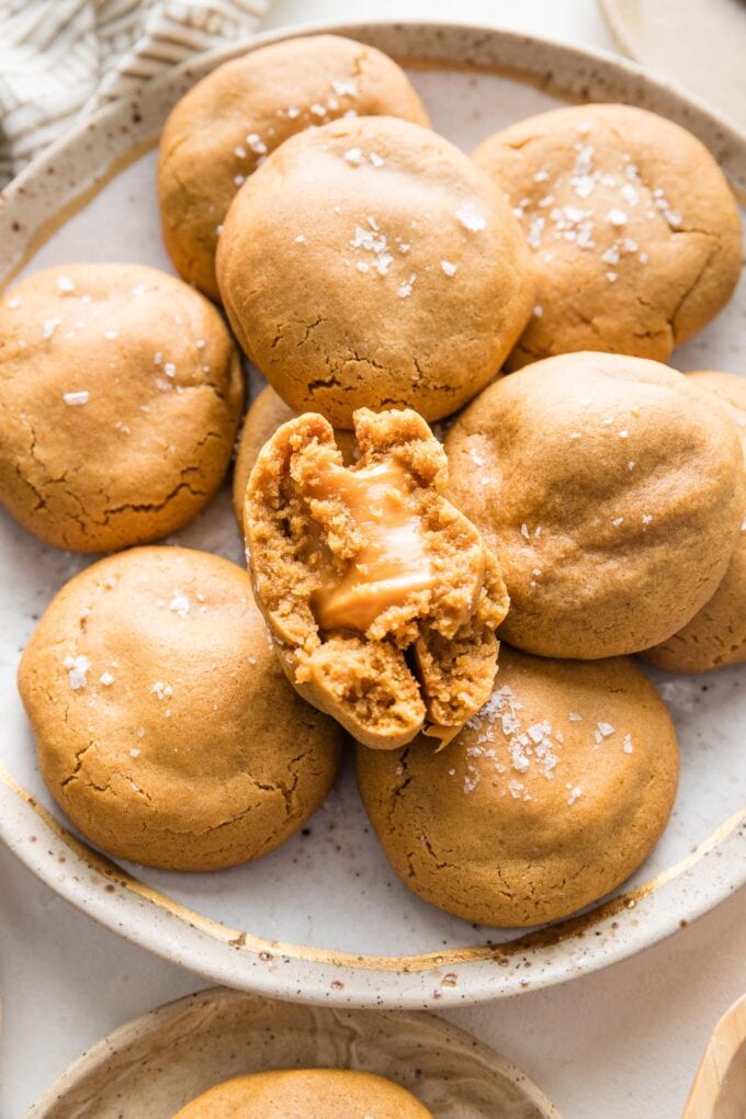 Close up image of a caramel-stuffed molasses cookie broken in half to show the chewy, stretchy caramel melted in the middle.