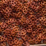 Sheet pan full of homemade honey mustard pretzels, with extra honey on the counter nearby.