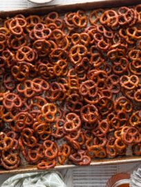 Sheet pan full of homemade honey mustard pretzels, with extra honey on the counter nearby.