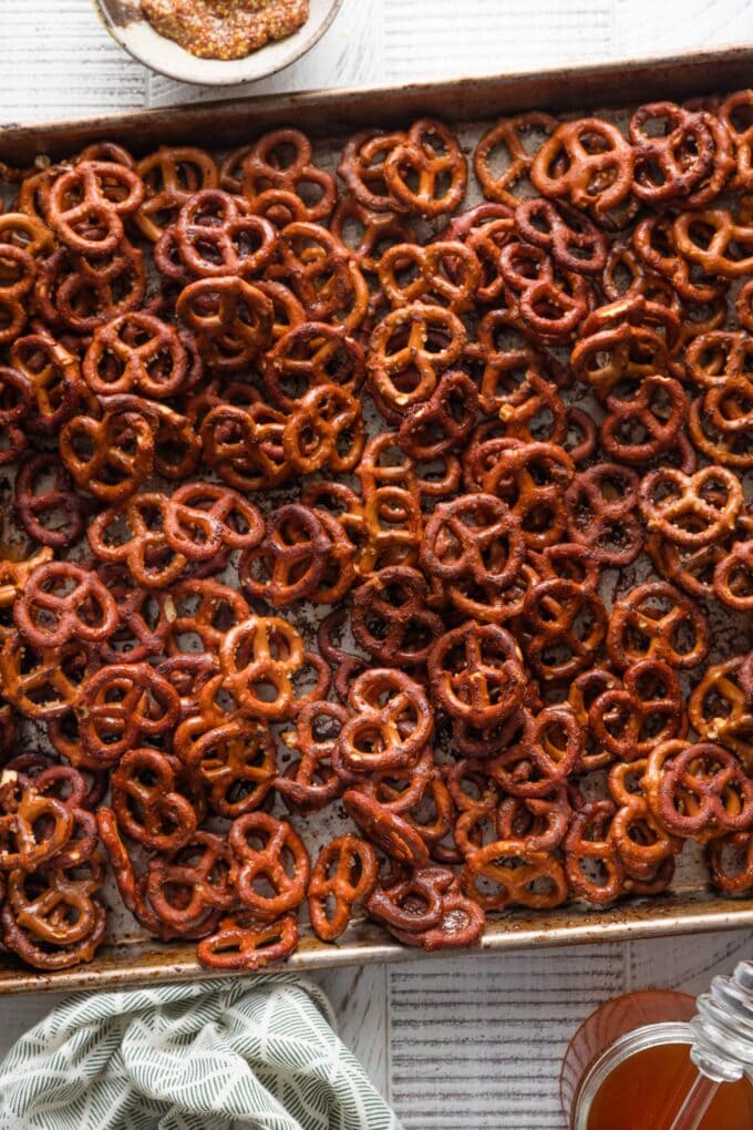 Sheet pan full of homemade honey mustard pretzels, with extra honey on the counter nearby.