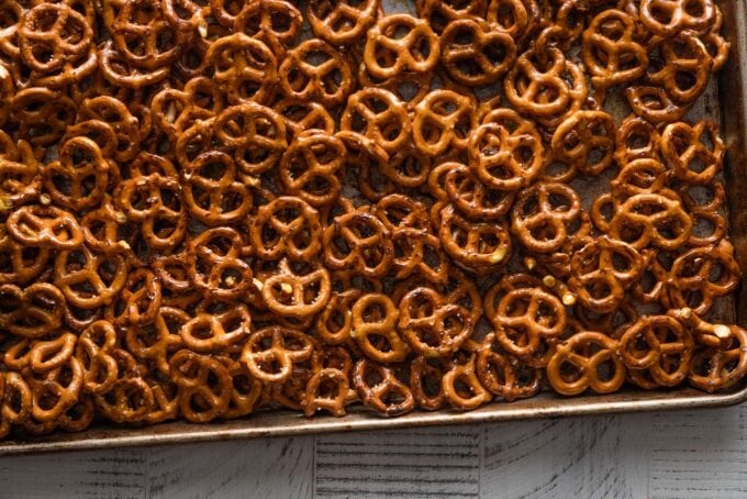 Landscape-oriented image of homemade honey mustard pretzels spread out on a large baking pan and just taken out of the oven.