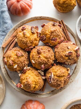 Small plate filled with pumpkin muffins topped with a brown sugar cinnamon pecan crunch topping.