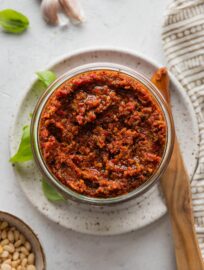 Glass jar full of homemade pesto rosso, ready to cover and store in the fridge.