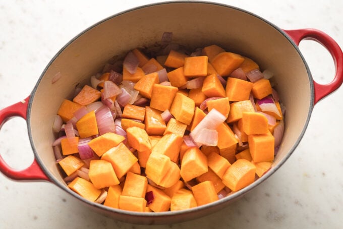 Dutch oven filled with diced sweet potato and red onion.