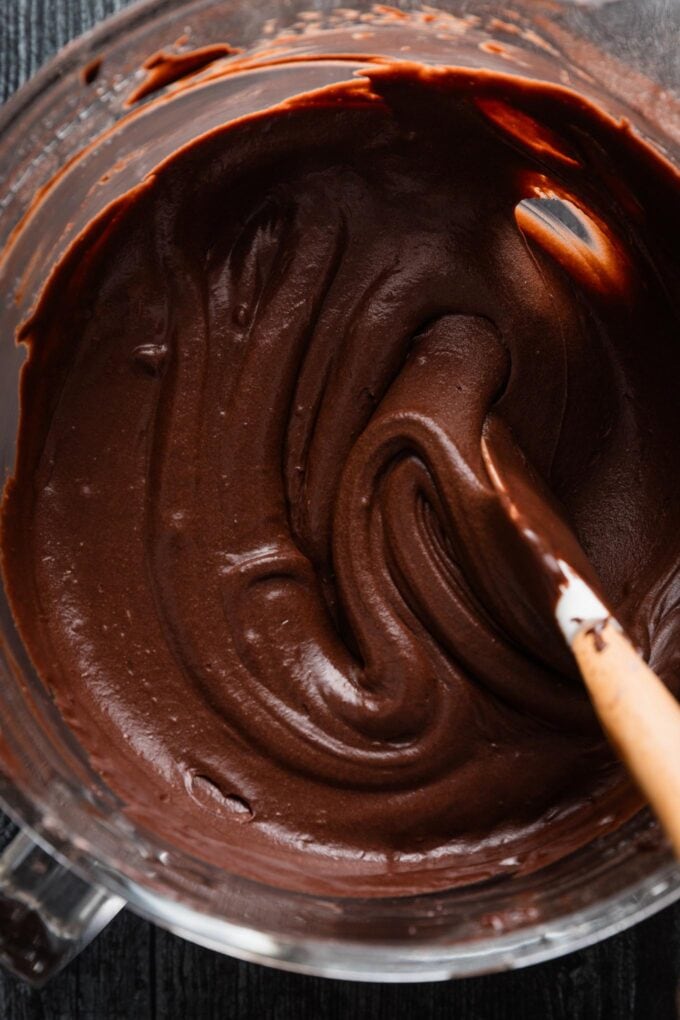 Silky smooth chocolate cake batter in a large clear glass bowl.