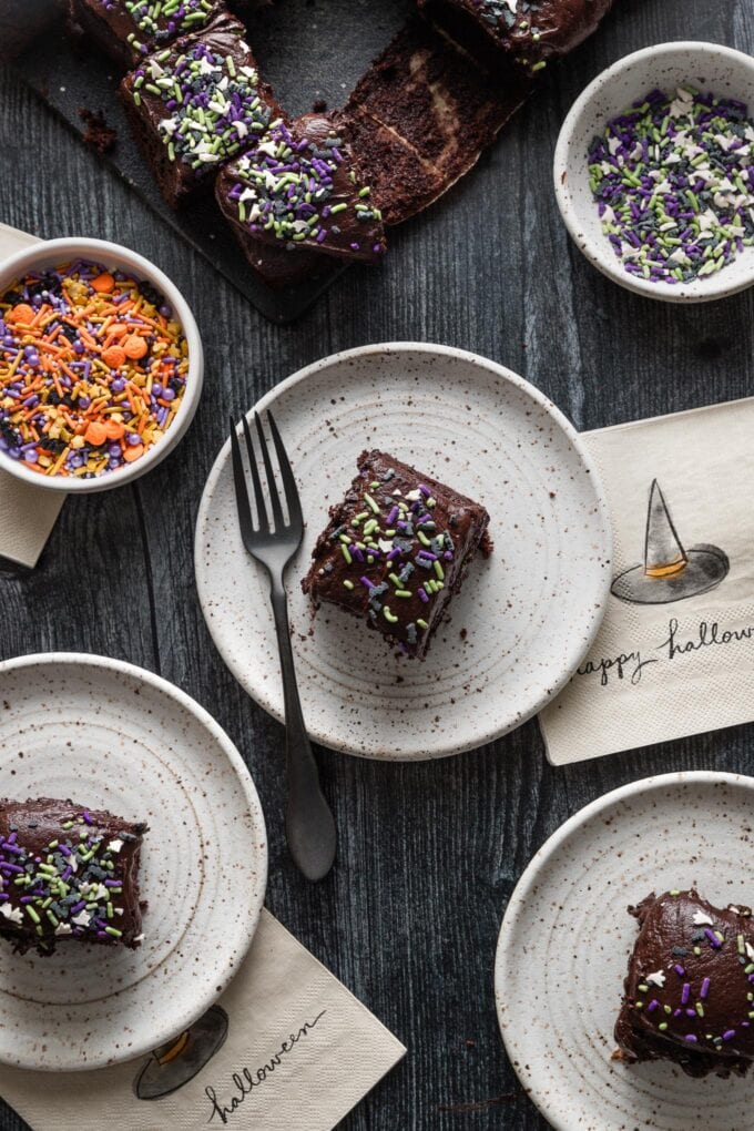 Dark table set with small plates of a Halloween-themed chocolate cake.