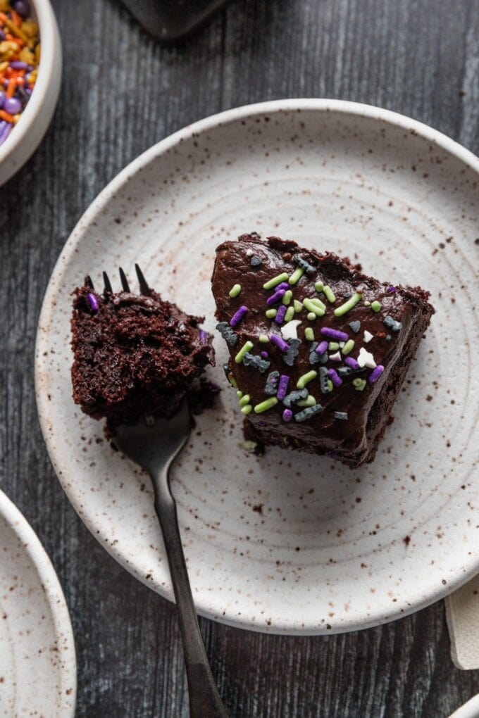 Close up of a small piece of blackout chocolate sheet cake, with a forkful removed to show how moist and tender the inside is.