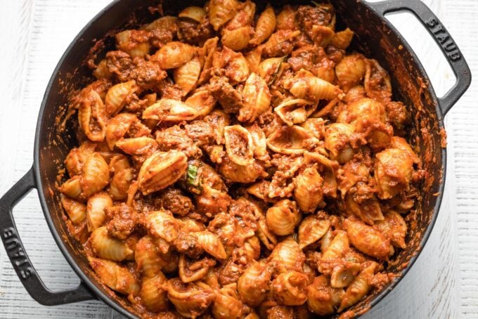 Weeknight bolognese sauce mixed with shells in a skillet.