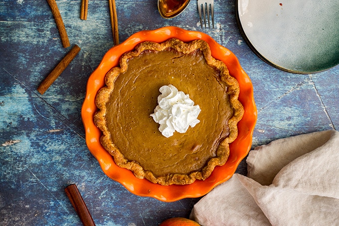 Overhead picture of a whole bourbon molasses-spiked pumpkin pie with a large dollop of whipped cream.