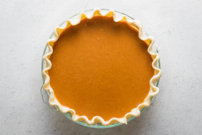 Unbaked pumpkin pie in a fluted pie crust.