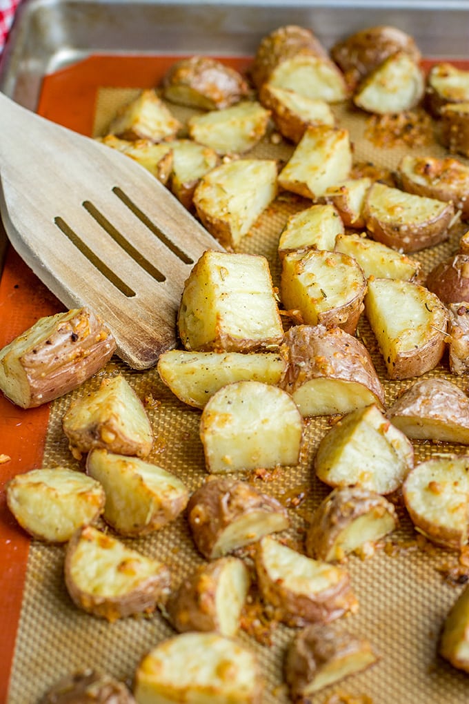 Close-up of parmesan herb crusted red potatoes, roasted on a baking sheet.
