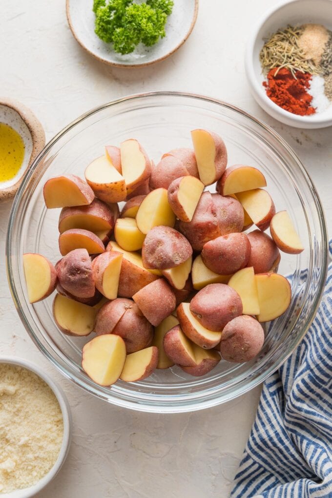 Quartered baby red potatoes in a clear glass prep bowl.