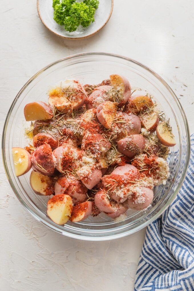 Baby potatoes tossed with olive oil, Parmesan, and herbs in a prep bowl.