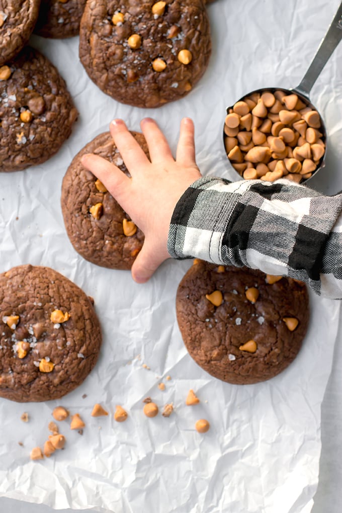 A cute, chubby toddler hand reaching for a chewy, toffee butterscotch brownie cookie.