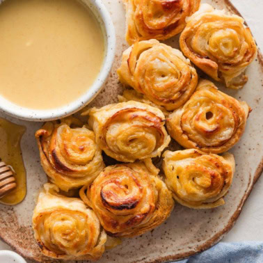 Small plate filled with turkey roll ups baked with Swiss cheese and a honey mustard glaze in between layers of crescent roll dough.