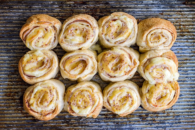 A baking sheet loaded with turkey gouda rolls ready for a party.