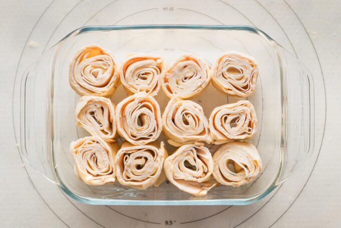Turkey party rolls sliced and arranged in a small baking pan.